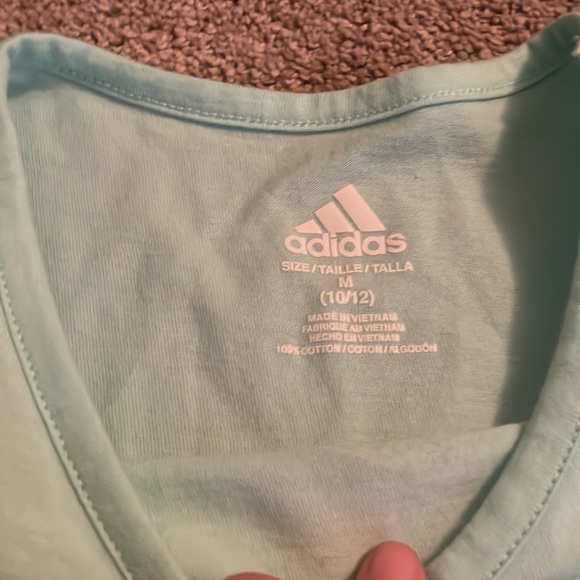 It is an Adidas t shirt and it is teal with sparkles as the logo. - Picture 2 of 2